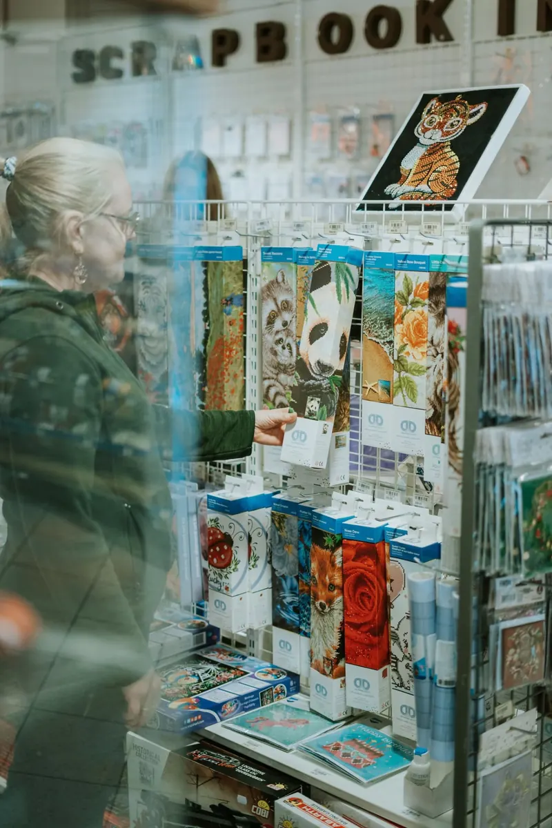 Ein tilsett viser fram broderi og hobbyartiklar i Bokuben-butikken